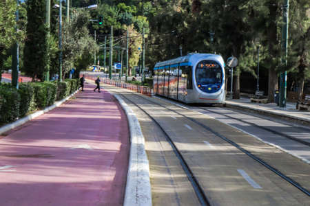 Athens, Greece - November 22, 2021 Modern electric tram for passengers rolling through the streets of Athens during the coronavirus outbreak hitting Greece, wearing a mask is mandatoryのeditorial素材