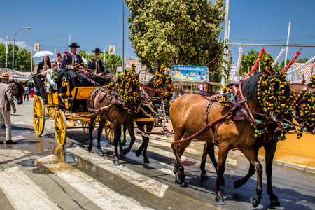 Seville, Spain - May 01, 2022 Sevillians dressed in the traditional Andalusian way riding in a horse drawn carriage through the aisles of the Feria de Sevilla, the most famous festival in Spainのeditorial素材