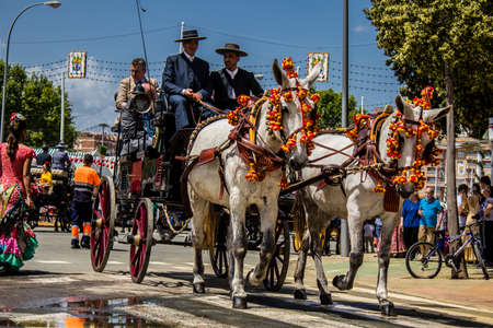 Seville, Spain - May 01, 2022 Sevillians dressed in the traditional Andalusian way riding in a horse drawn carriage through the aisles of the Feria de Sevilla, the most famous festival in Spainのeditorial素材