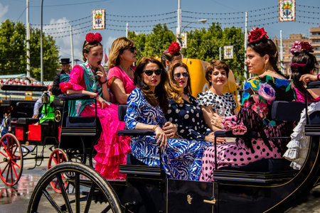 Seville, Spain - May 01, 2022 Sevillians dressed in the traditional Andalusian way riding in a horse drawn carriage through the aisles of the Feria de Sevilla, the most famous festival in Spainのeditorial素材