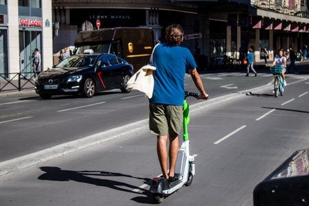 Paris, France - September 14, 2022 People rolling with an electric scooter in the streets of Paris, operating with a small utility internal combustion engines and a deck in the centerのeditorial素材