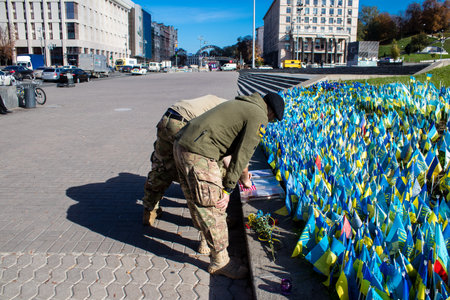 3 soldiers of the foreign legion in Ukraine, of American, Canadian and Belgian nationality pay homage to one of their killed in action in Kherson during the fights with the Russian army. A small flag with the name of the dead soldier is planted in the maiのeditorial素材