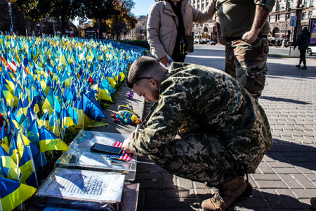3 soldiers of the foreign legion in Ukraine, of American, Canadian and Belgian nationality pay homage to one of their killed in action in Kherson during the fights with the Russian army. A small flag with the name of the dead soldier is planted in the maiのeditorial素材