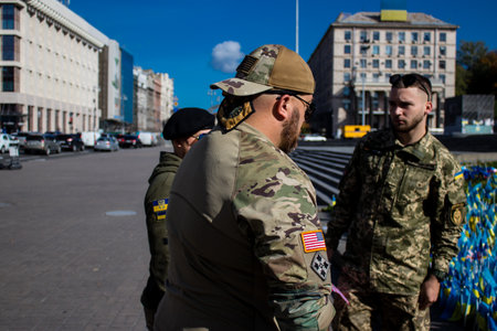 3 soldiers of the foreign legion in Ukraine, of American, Canadian and Belgian nationality pay homage to one of their killed in action in Kherson during the fights with the Russian army. A small flag with the name of the dead soldier is planted in the maiのeditorial素材
