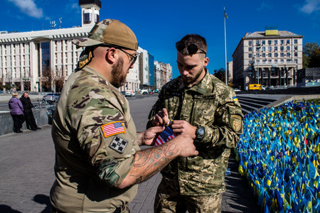 3 soldiers of the foreign legion in Ukraine, of American, Canadian and Belgian nationality pay homage to one of their killed in action in Kherson during the fights with the Russian army. A small flag with the name of the dead soldier is planted in the maiのeditorial素材