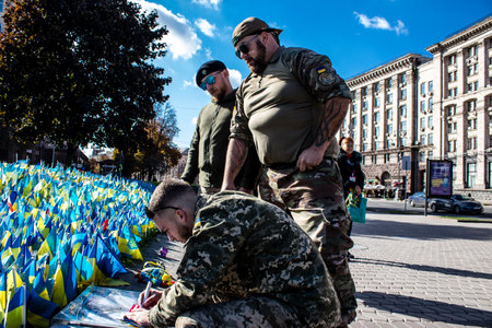 3 soldiers of the foreign legion in Ukraine, of American, Canadian and Belgian nationality pay homage to one of their killed in action in Kherson during the fights with the Russian army. A small flag with the name of the dead soldier is planted in the maiのeditorial素材