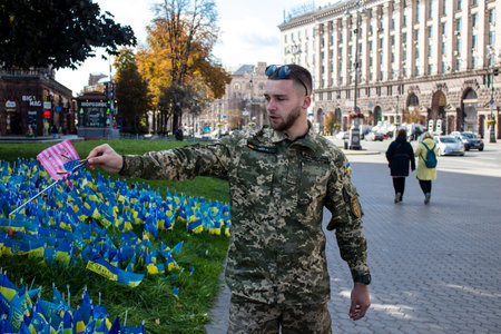 3 soldiers of the foreign legion in Ukraine, of American, Canadian and Belgian nationality pay homage to one of their killed in action in Kherson during the fights with the Russian army. A small flag with the name of the dead soldier is planted in the maiのeditorial素材