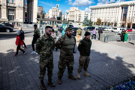 3 soldiers of the foreign legion in Ukraine, of American, Canadian and Belgian nationality pay homage to one of their killed in action in Kherson during the fights with the Russian army. A small flag with the name of the dead soldier is planted in the maiのeditorial素材