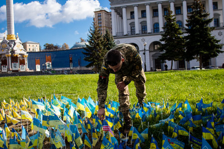 3 soldiers of the foreign legion in Ukraine, of American, Canadian and Belgian nationality pay homage to one of their killed in action in Kherson during the fights with the Russian army. A small flag with the name of the dead soldier is planted in the maiのeditorial素材