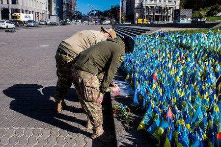 3 soldiers of the foreign legion in Ukraine, of American, Canadian and Belgian nationality pay homage to one of their killed in action in Kherson during the fights with the Russian army. A small flag with the name of the dead soldier is planted in the maiのeditorial素材