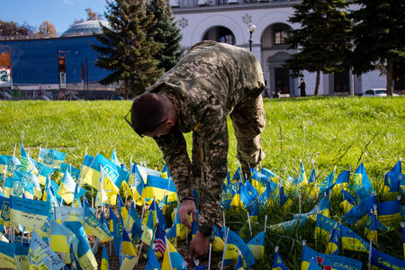 3 soldiers of the foreign legion in Ukraine, of American, Canadian and Belgian nationality pay homage to one of their killed in action in Kherson during the fights with the Russian army. A small flag with the name of the dead soldier is planted in the maiのeditorial素材