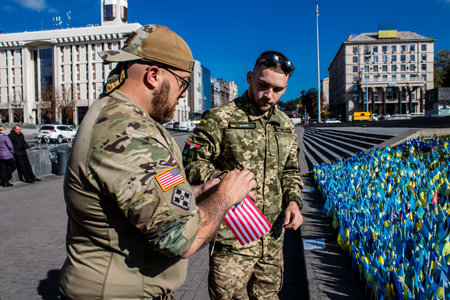 3 soldiers of the foreign legion in Ukraine, of American, Canadian and Belgian nationality pay homage to one of their killed in action in Kherson during the fights with the Russian army. A small flag with the name of the dead soldier is planted in the maiのeditorial素材