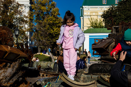 Ukrainian children have fun on the destroyed Russian military equipment, they use it like a playground. The destroyed Russian military equipment exhibition is an open air exhibition.のeditorial素材