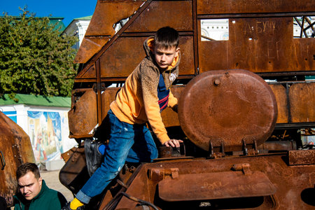 Ukrainian children have fun on the destroyed Russian military equipment, they use it like a playground. The destroyed Russian military equipment exhibition is an open air exhibition.のeditorial素材