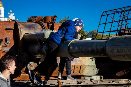 Ukrainian children have fun on the destroyed Russian military equipment, they use it like a playground. The destroyed Russian military equipment exhibition is an open air exhibition.のeditorial素材