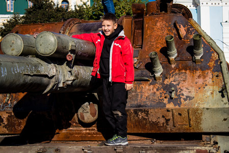 Ukrainian children have fun on the destroyed Russian military equipment, they use it like a playground. The destroyed Russian military equipment exhibition is an open air exhibition.のeditorial素材