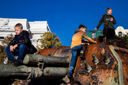 Ukrainian children have fun on the destroyed Russian military equipment, they use it like a playground. The destroyed Russian military equipment exhibition is an open air exhibition.のeditorial素材
