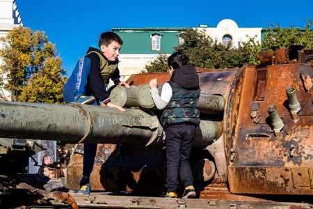 Ukrainian children have fun on the destroyed Russian military equipment, they use it like a playground. The destroyed Russian military equipment exhibition is an open air exhibition.のeditorial素材