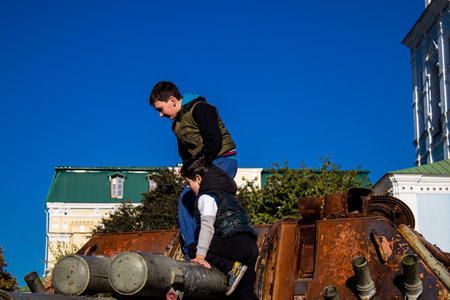 Ukrainian children have fun on the destroyed Russian military equipment, they use it like a playground. The destroyed Russian military equipment exhibition is an open air exhibition.のeditorial素材