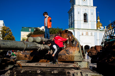 Ukrainian children have fun on the destroyed Russian military equipment, they use it like a playground. The destroyed Russian military equipment exhibition is an open air exhibition.のeditorial素材