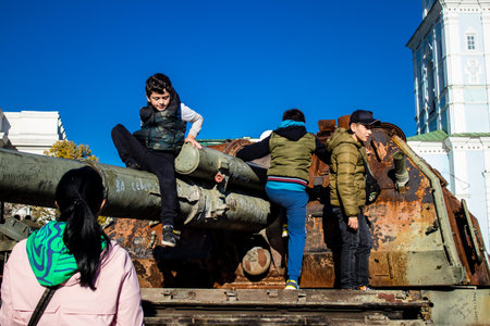 Ukrainian children have fun on the destroyed Russian military equipment, they use it like a playground. The destroyed Russian military equipment exhibition is an open air exhibition.のeditorial素材