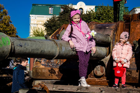 Ukrainian children have fun on the destroyed Russian military equipment, they use it like a playground. The destroyed Russian military equipment exhibition is an open air exhibition.のeditorial素材