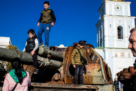 Ukrainian children have fun on the destroyed Russian military equipment, they use it like a playground. The destroyed Russian military equipment exhibition is an open air exhibition.のeditorial素材