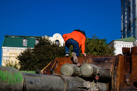 Ukrainian children have fun on the destroyed Russian military equipment, they use it like a playground. The destroyed Russian military equipment exhibition is an open air exhibition.のeditorial素材