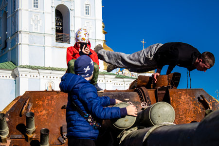Ukrainian children have fun on the destroyed Russian military equipment, they use it like a playground. The destroyed Russian military equipment exhibition is an open air exhibition.のeditorial素材