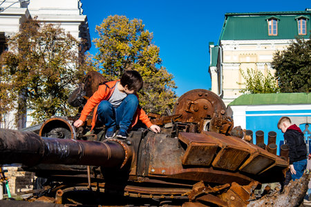 Ukrainian children have fun on the destroyed Russian military equipment, they use it like a playground. The destroyed Russian military equipment exhibition is an open air exhibition.のeditorial素材