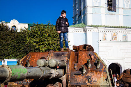 Ukrainian children have fun on the destroyed Russian military equipment, they use it like a playground. The destroyed Russian military equipment exhibition is an open air exhibition.のeditorial素材