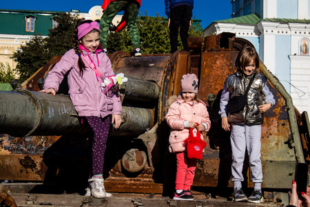 Ukrainian children have fun on the destroyed Russian military equipment, they use it like a playground. The destroyed Russian military equipment exhibition is an open air exhibition.のeditorial素材