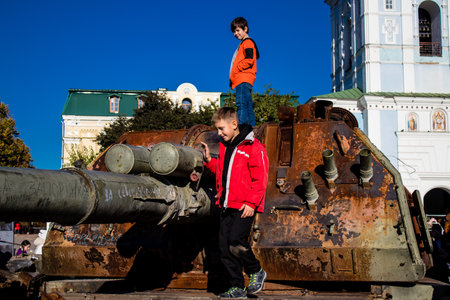 Ukrainian children have fun on the destroyed Russian military equipment, they use it like a playground. The destroyed Russian military equipment exhibition is an open air exhibition.のeditorial素材