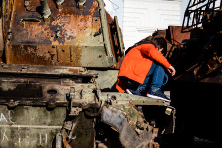 Ukrainian children have fun on the destroyed Russian military equipment, they use it like a playground. The destroyed Russian military equipment exhibition is an open air exhibition.のeditorial素材