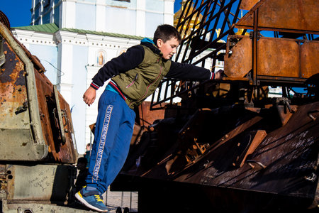 Ukrainian children have fun on the destroyed Russian military equipment, they use it like a playground. The destroyed Russian military equipment exhibition is an open air exhibition.のeditorial素材
