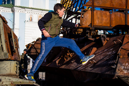 Ukrainian children have fun on the destroyed Russian military equipment, they use it like a playground. The destroyed Russian military equipment exhibition is an open air exhibition.のeditorial素材