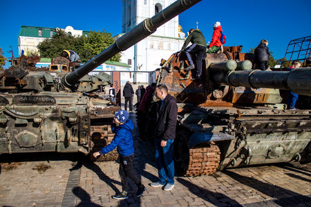 Ukrainian children have fun on the destroyed Russian military equipment, they use it like a playground. The destroyed Russian military equipment exhibition is an open air exhibition.のeditorial素材