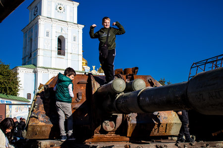 Ukrainian children have fun on the destroyed Russian military equipment, they use it like a playground. The destroyed Russian military equipment exhibition is an open air exhibition.のeditorial素材
