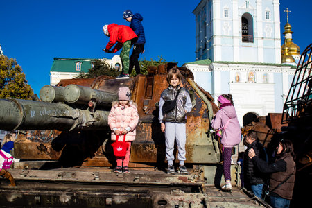Ukrainian children have fun on the destroyed Russian military equipment, they use it like a playground. The destroyed Russian military equipment exhibition is an open air exhibition.のeditorial素材