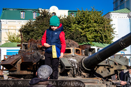 Ukrainian children have fun on the destroyed Russian military equipment, they use it like a playground. The destroyed Russian military equipment exhibition is an open air exhibition.のeditorial素材