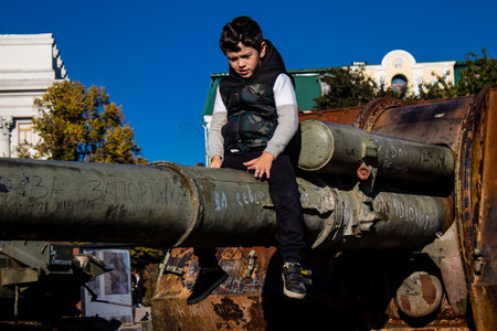 Ukrainian children have fun on the destroyed Russian military equipment, they use it like a playground. The destroyed Russian military equipment exhibition is an open air exhibition.のeditorial素材