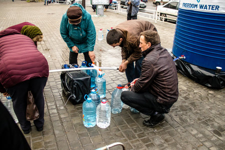 Residents of Kherson in Ukraine, collecting drinkable water at Freedom Square. International humanitarian aid is organized when people lack everything. The Russian army has bombed the infrastructure of the city and the water supply is completely cut off. のeditorial素材