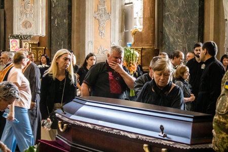 Lviv, Ukraine, August 23, 2024 Relatives are crying on the coffin. Religious ceremony in the Church of the Most Holy Apostles Peter and Paul for three soldiers who died in a battle with the Russian.のeditorial素材