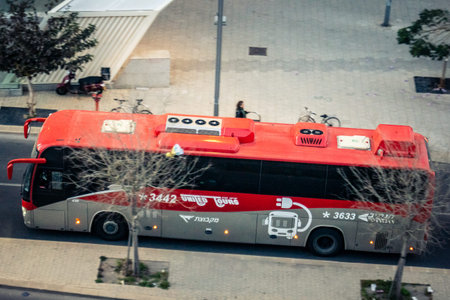 Tel Aviv, Israel - February 23, 2026: A modern electric bus drives through the city streets. Tel Aviv is expanding its green public transportation network to provide sustainable and eco-friendly mobility for its citizens.のeditorial素材