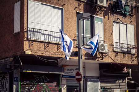 Tel Aviv, Israel, March 12, 2026 The national flag of Israel with the Star of David and the municipal flag of Tel Aviv-Yafo fly side by side in a public street. These symbols represent national pride and local identity in the Israeli metropolis.のeditorial素材
