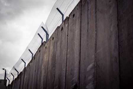 Bethlehem, West Bank, Palestine, March 23, 2026 Sharp coils of razor wire and heavy duty security fencing reinforce the concrete panels of the Israeli separation barrier. This physical obstruction serves as a stark reminder of the restricted movement and のeditorial素材
