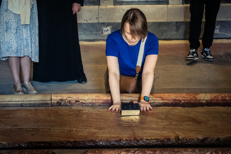 JERUSALEM, ISRAEL - FEBRUARY 16, 2026 Close-up of Christian pilgrims touching and blessing the Stone of Anointing in the Church of the Holy Sepulchre. Sacred ritual of faith and devotion.のeditorial素材