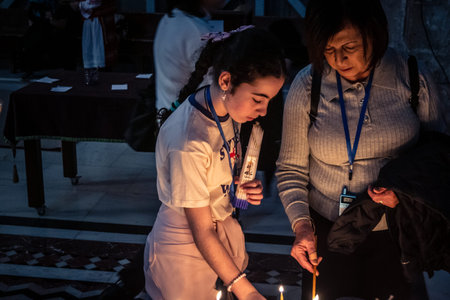 JERUSALEM, ISRAEL - FEBRUARY 21, 2026 Christian pilgrims lighting prayer candles in the mystic and sacred darkness of the Church of the Holy Sepulchre. Spiritual atmosphere and deep religious fervor.のeditorial素材