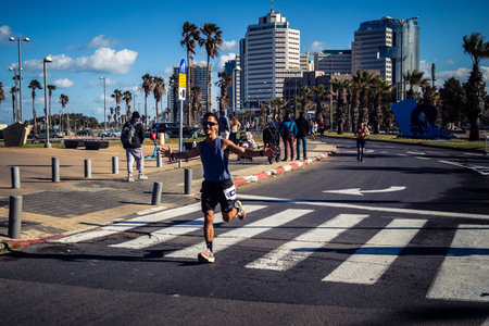 Tel Aviv, Israel, February 27, 2026 A participant makes direct eye contact and waves at the camera, capturing a moment of personal connection and endurance during the city marathon.のeditorial素材