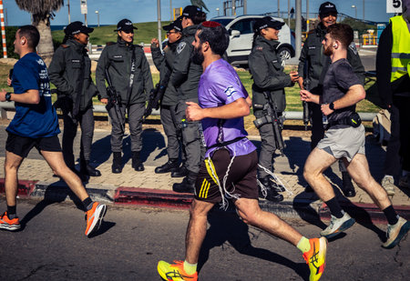 Tel Aviv, Israel, February 27, 2026 Marathon participants run past security forces standing guard along the promenade, showing the high-security environment.のeditorial素材